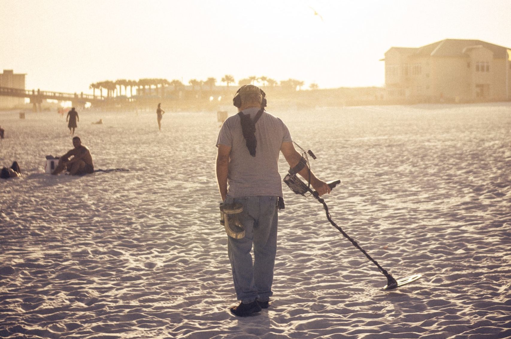 Mann beim Sondeln mit Metalldetektor am Strand