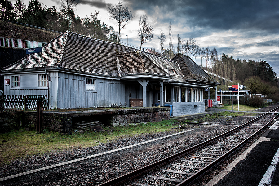 Historisches Bahnhofsgebäude in Schopp mit Gleisen im Vordergrund